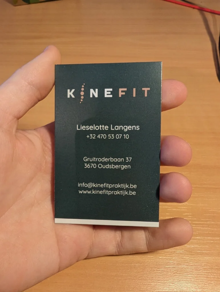 Gedrukt kaartje van Kinefit in de hand, met het logo en de contactgegevens van kinesitherapeut Lieselotte Langens