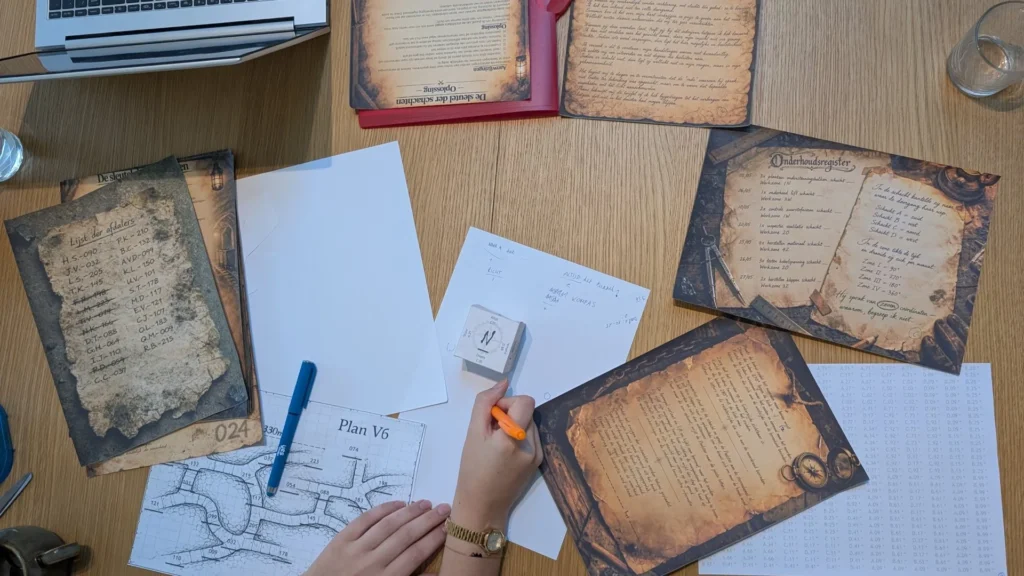 Spelers lossen de papieren escape room De Laatste Schacht op aan tafel, met brieven, registers en het grondplan